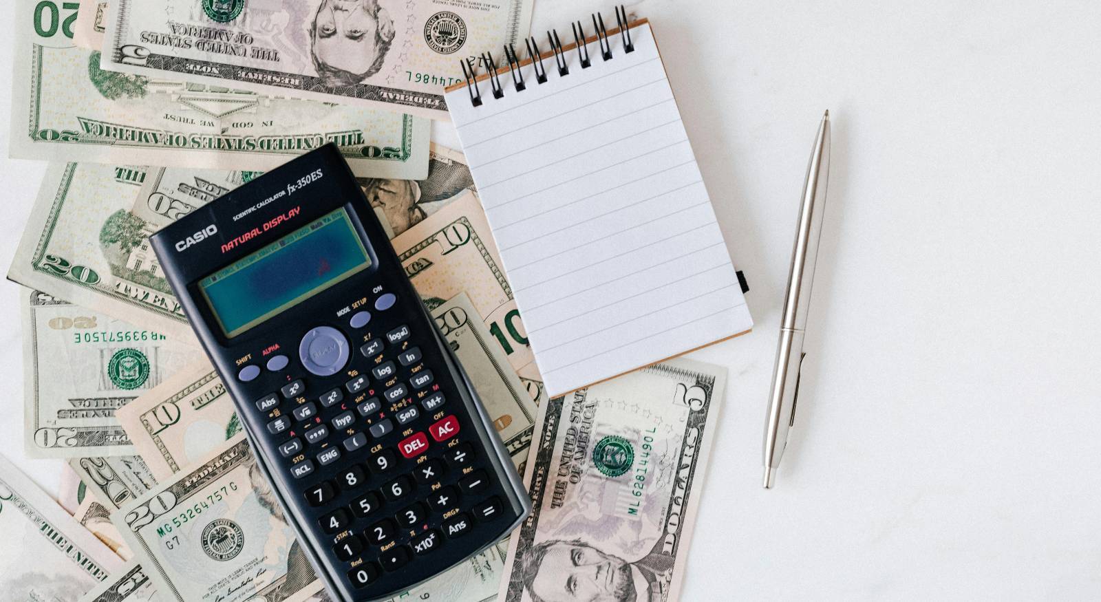 A calculator and a notebook with money in a table