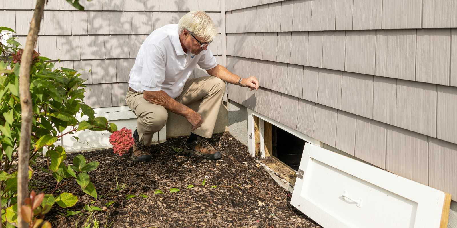 A man checking a crawl space during spring