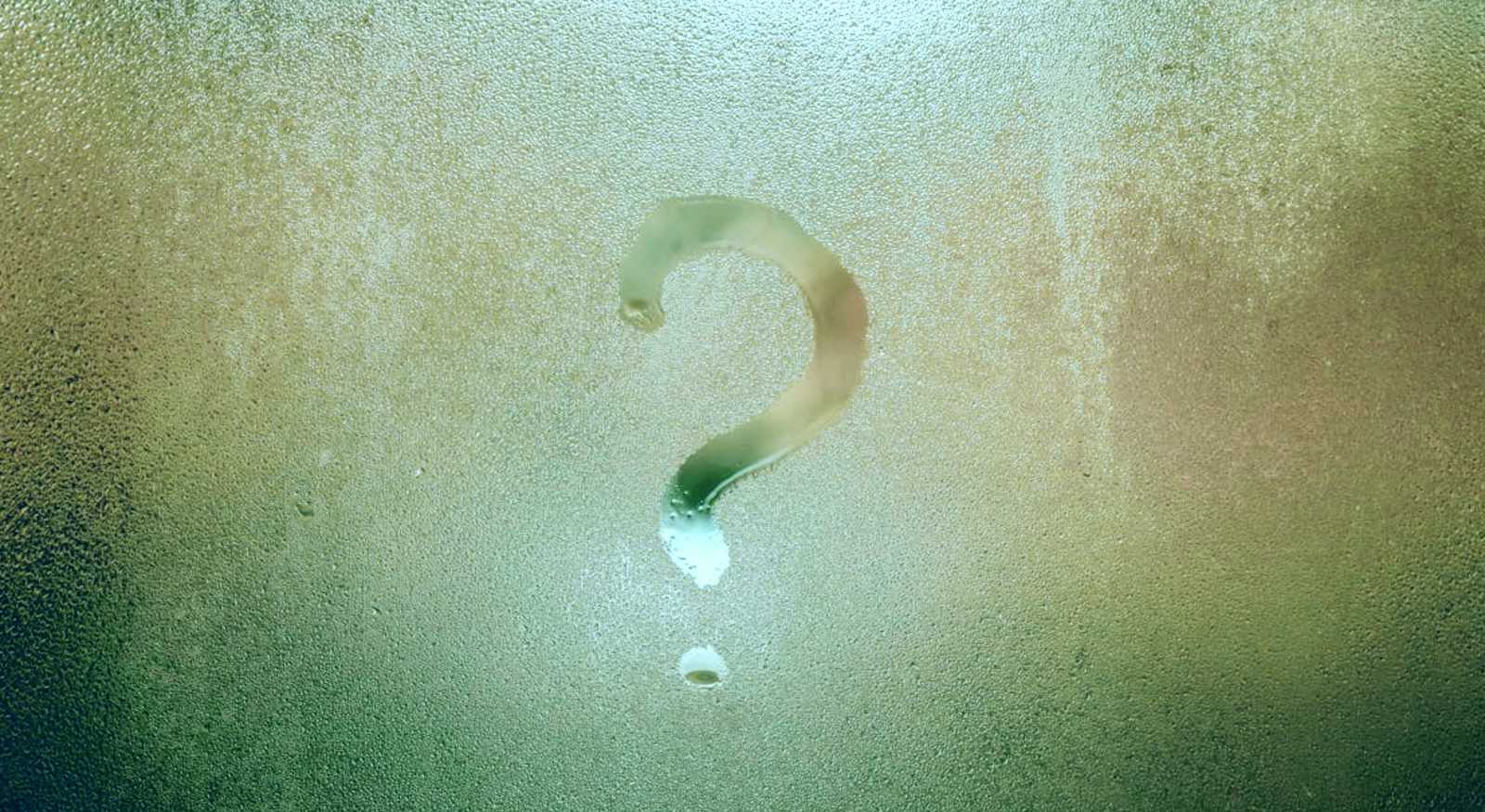 A window showing condensation with a question mark made with the droplets